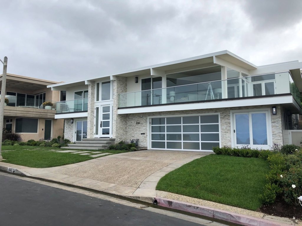 Modern coastal home with stacked-stone facade and glass railings