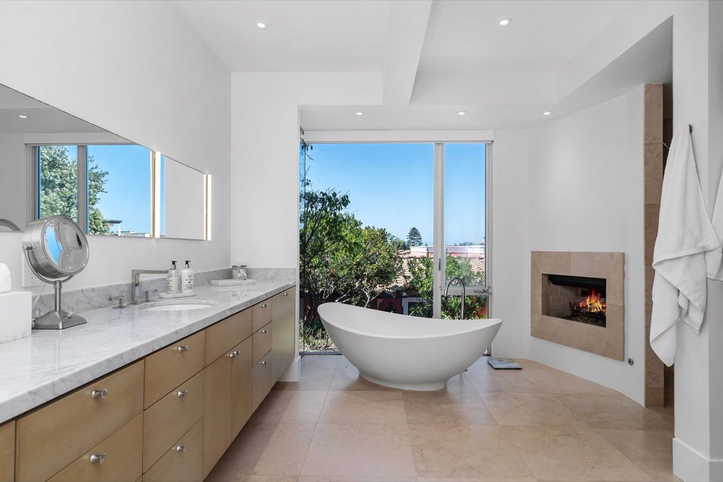 Primary bath with freestanding tub, marble vanity and a fireplace