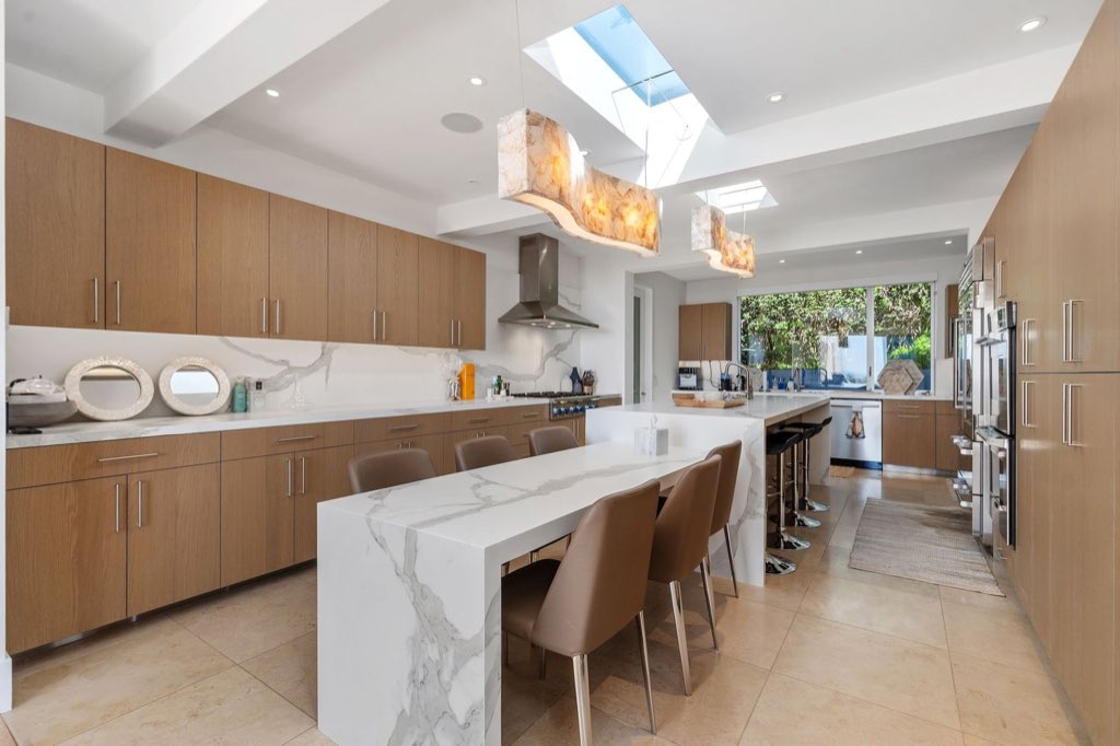 Rift oak kitchen with waterfall marble island and onyx pendants under skylights