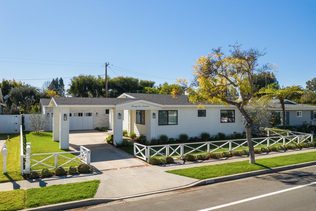 Single-story coastal cottage behind a white picket fence