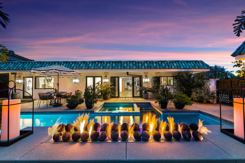 Courtyard ranch at dusk with pool and fire feature